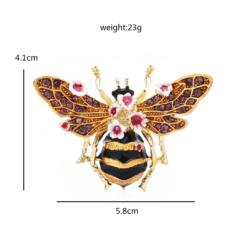 Broche abeille à fleurs dorée avec ailes décorées de strass violets et petites fleurs roses, vue de face