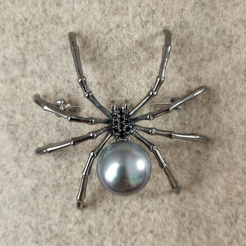Broche araignée à perle avec corps argenté et perle grise ronde, détail soigné des pattes métalliques articulées