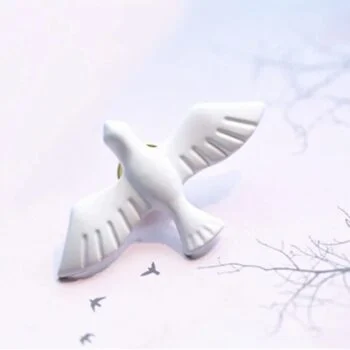 Broche blanche en forme de colombe avec ailes déployées en matière lisse