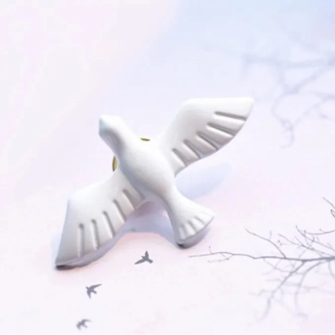 Broche blanche en forme de colombe avec ailes déployées en matière lisse