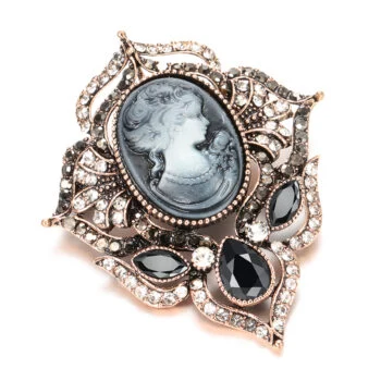 Broche camée femme en métal doré avec portrait féminin en relief, ornée de strass blancs et pierres noires facettées, design travaillé avec détail élégant