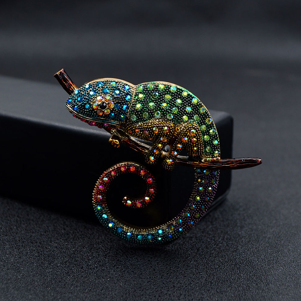 Broche caméléon coloré en métal orné de strass bleus, verts et rouges, vue de profil mettant en avant la spirale de la queue et les détails scintillants