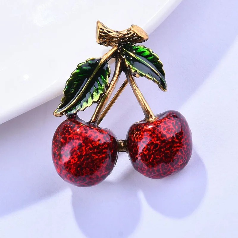 Broche cerises rouge et vert en métal doré avec feuilles émaillées, détail soigné et finition élégante