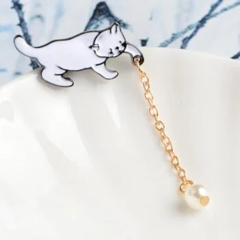 Broche chat blanc en métal avec chaîne dorée et perle suspendue, détail élégant