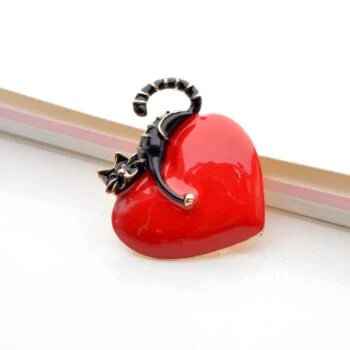 Broche chat noir posé sur un cœur rouge brillant en émail