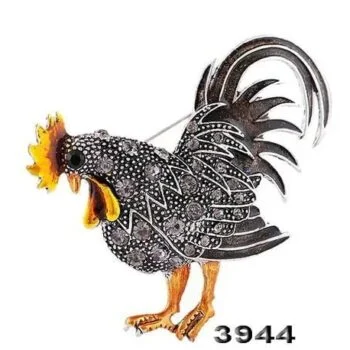 Broche Coq Fantaisie en métal noir et argenté avec détails orange, vue de profil montrant le plumage stylisé et le bec ouvert