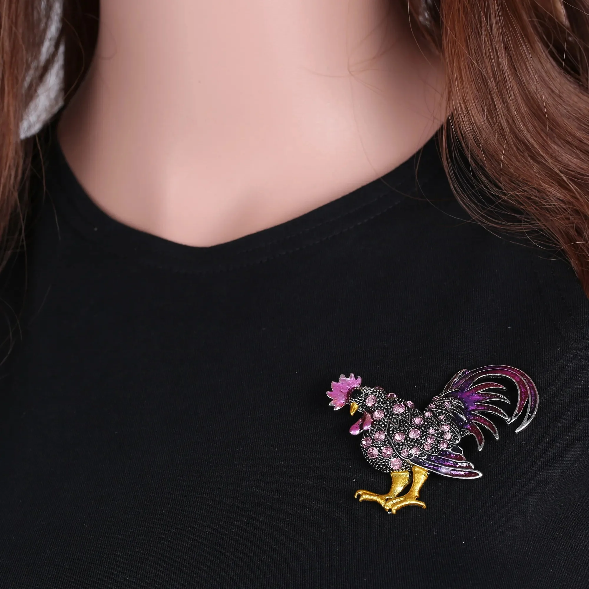 Broche coq fantaisie en métal avec strass multicolores posée sur un vêtement noir, détail du motif et des couleurs vives