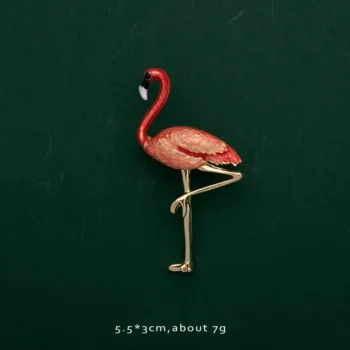 Broche flamant rose rouge en métal avec détail soigné sur fond vert