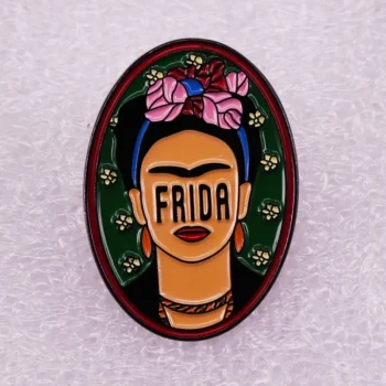 Broche Frida Kahlo ovale en émail avec visage stylisé, fleurs roses et fond vert
