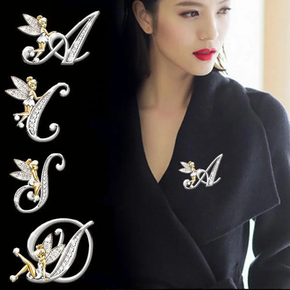 Broche grandes lettres en métal argenté avec détails dorés et strass, modèle A, portée sur un manteau noir