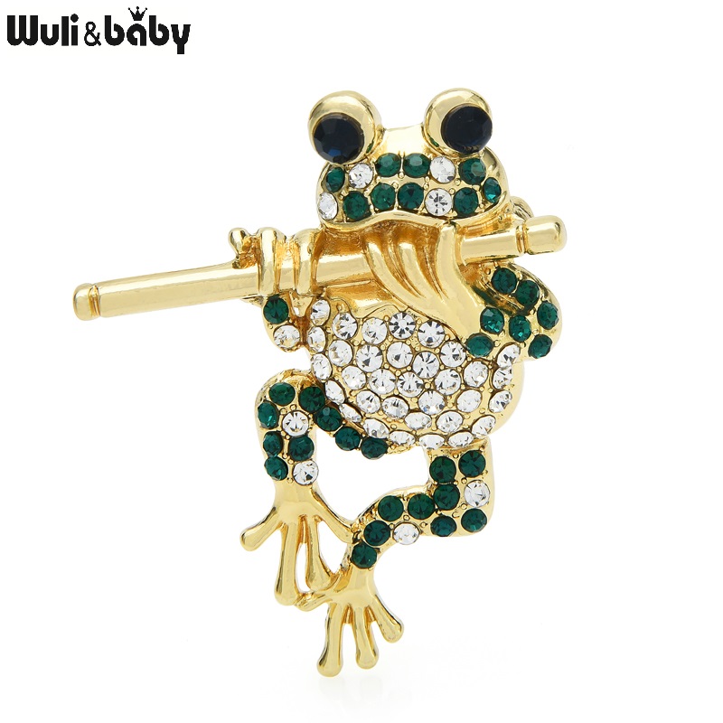 Broche grenouille dorée à la flûte ornée de strass verts et blancs, détail soigné et finition élégante