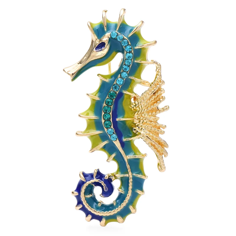 Broche hippocampe en métal doré avec émail bleu et vert, ornée de strass bleus sur le corps et détail aile texturé