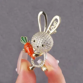 Broche lapin en strass argenté tenant une carotte orange avec feuilles vertes, détail du visage et oreilles avec inscription love