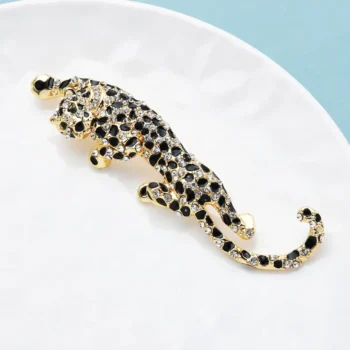 Broche léopard en métal doré avec strass noirs et transparents vue de côté sur fond clair