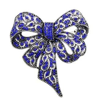 Broche nœud papillon fantaisie en métal argenté avec strass bleus et noirs, motif ajouré et finition soignée