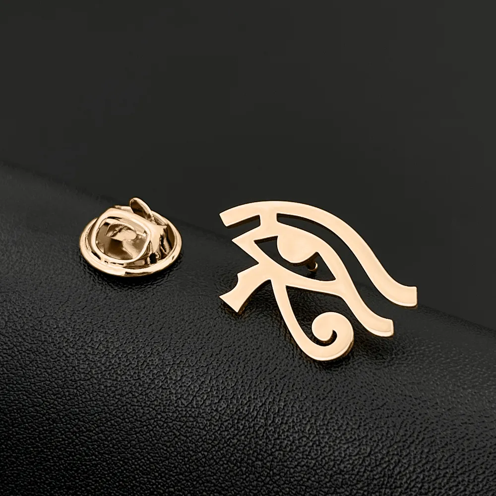 Broche Œil D'Horus dorée en métal avec fermoir papillon visible de face sur fond noir