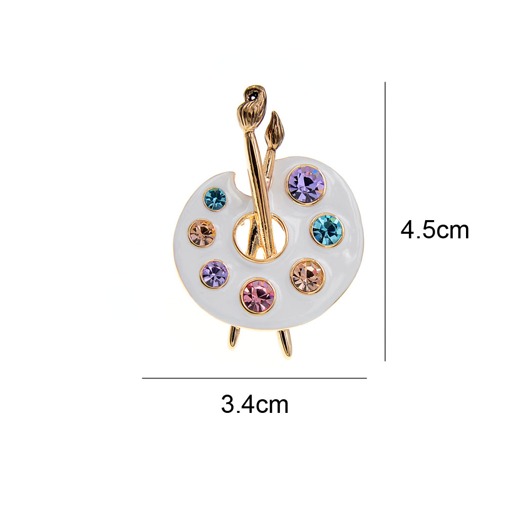 Broche palette de peintre blanche en métal doré avec strass colorés, dimensions 4.5 cm sur 3.4 cm