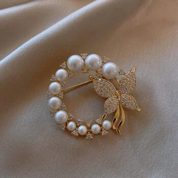 Broche papillon en métal doré avec perles blanches et strass, cercle orné de perles de différentes tailles et papillon décoré de petits strass