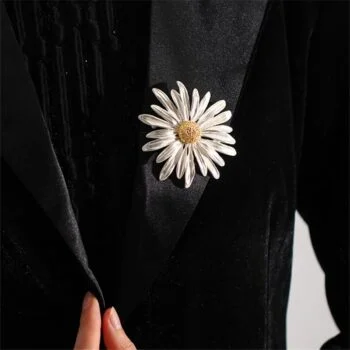 Broche Pâquerette blanche et jaune en métal émaillé portée sur un vêtement noir, vue de face sur le détail du bijou floral