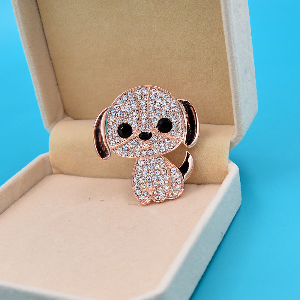 Broche petit chien en strass avec finition dorée, vue de face dans un écrin beige