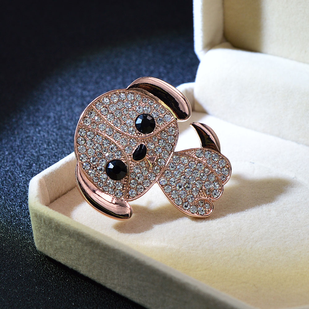 Broche Petit Chien en métal doré rose avec strass blancs et noirs, vue en gros plan dans un écrin beige