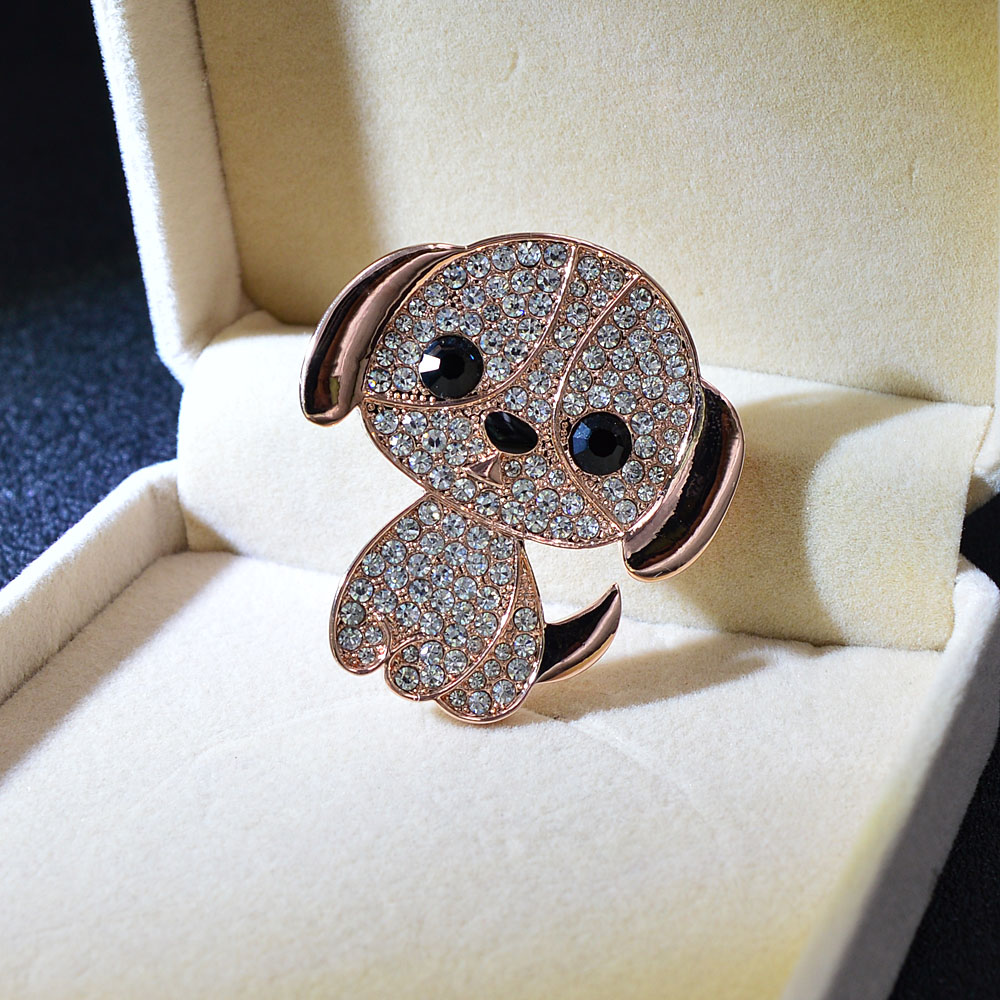 Broche petit chien en strass avec détails en métal doré rose, vue en léger angle dans écrin beige