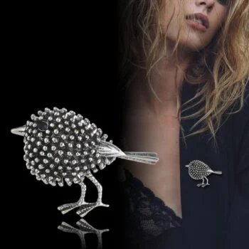 Broche petit oiseau en métal argenté avec finition texturée à picots, vue détaillée du bijou porté sur un vêtement noir