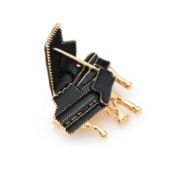 Broche piano noir et doré en métal avec détails en relief et finition soignée