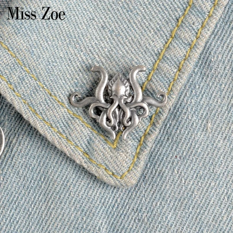 Broche pieuvre en métal argenté fixée sur un col de veste en jean bleu clair avec couture jaune
