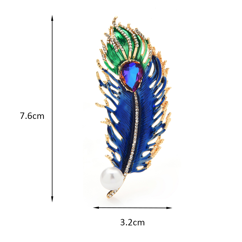 Broche Plume en métal doré avec émail bleu et vert, détail d'une pierre violette centrale et perle blanche, dimensions 7,6 cm sur 3,2 cm