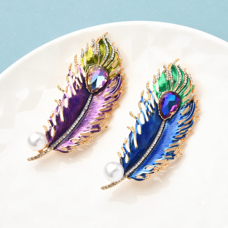 Broche plume en métal doré avec émail bleu et violet, détail perle blanche et motif plume stylisée