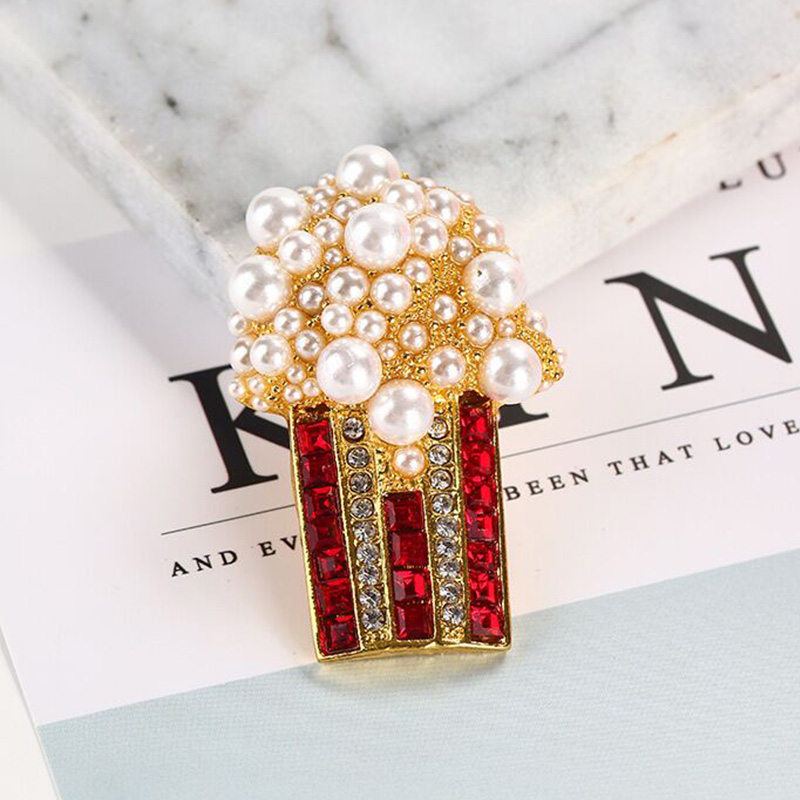 Broche Pop Corn Fantaisie avec perles blanches et strass rouges et noirs sur métal doré, détail soigné et design élégant