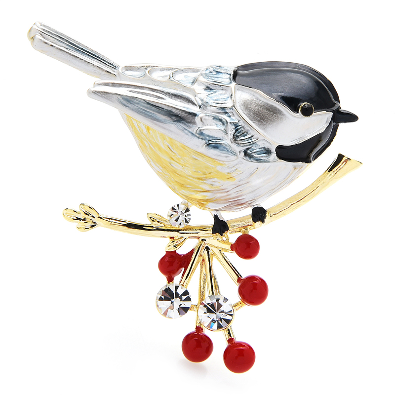 Broche Rouge Gorge en métal argenté et émaillé avec plumage noir, blanc et jaune, posée sur une branche dorée ornée de baies rouges et cristaux transparents