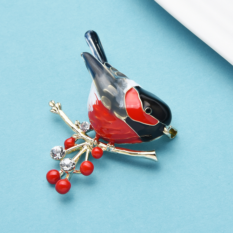 Broche Rouge Gorge en métal émaillé rouge et noir posée sur une branche dorée ornée de perles rouges et strass transparents