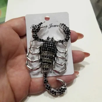 Broche scorpion vintage en métal argenté avec strass noirs, vue de face montrant les détails des pattes et de la queue enroulée