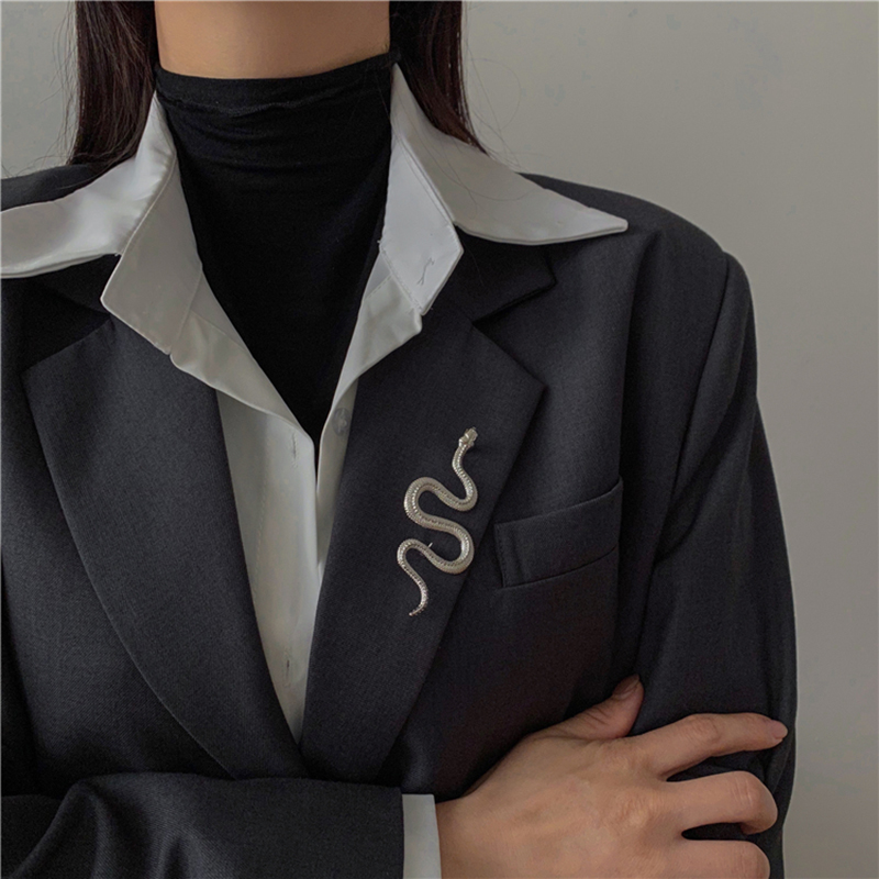 Broche serpent argentée en métal avec finition détaillée portée sur le revers d'un blazer noir
