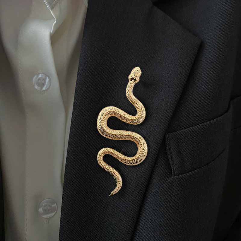 Broche serpent dorée en métal avec finition détaillée portée sur un revers de veste noire