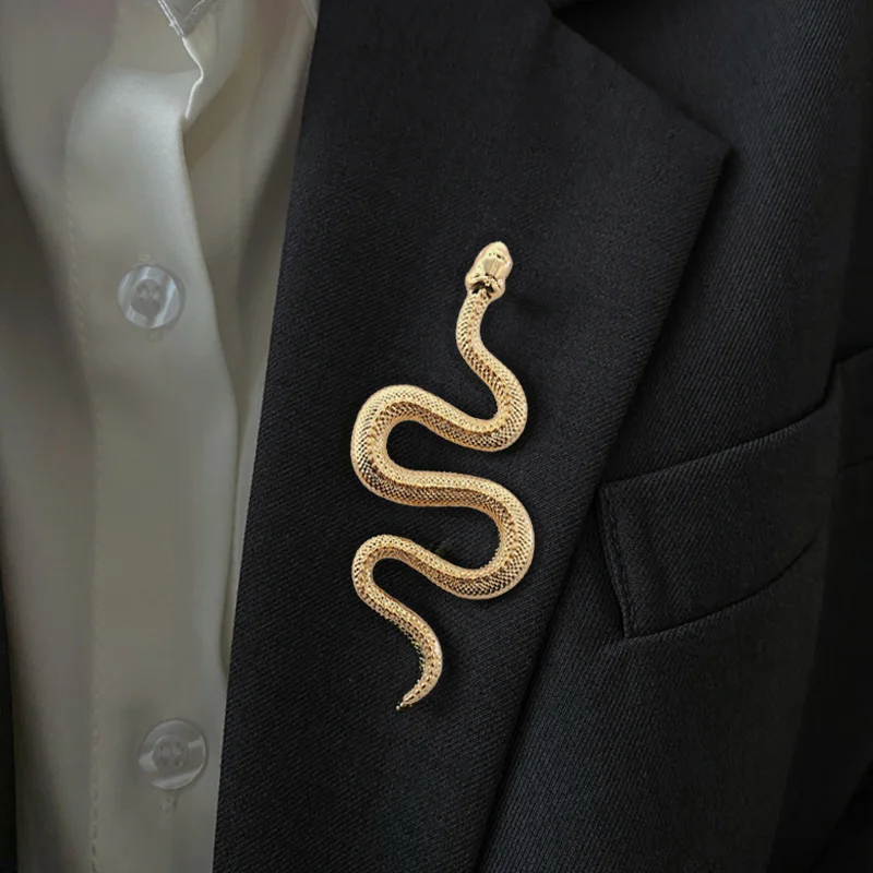 Broche serpent dorée en métal avec finition détaillée portée sur un revers de veste noire