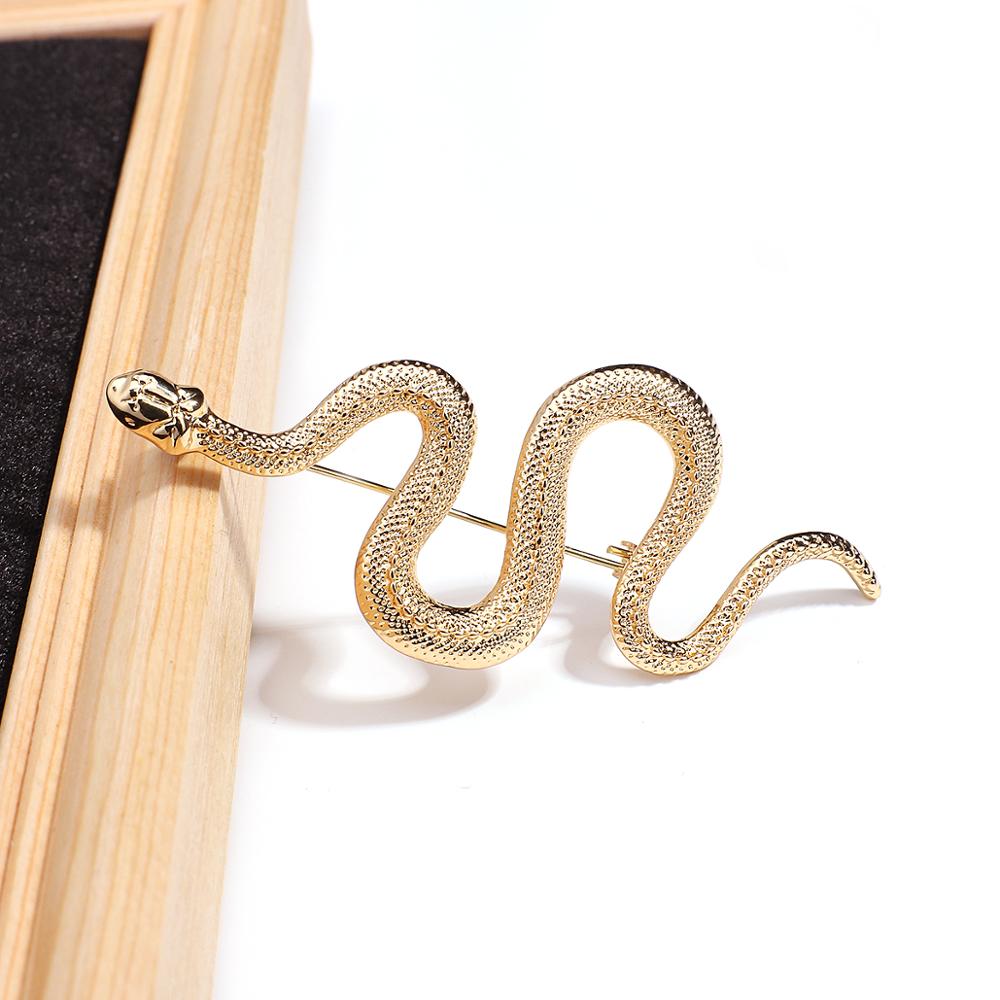 Broche serpent dorée en métal avec texture écaille détaillée, vue de profil mettant en valeur la forme ondulée du bijou