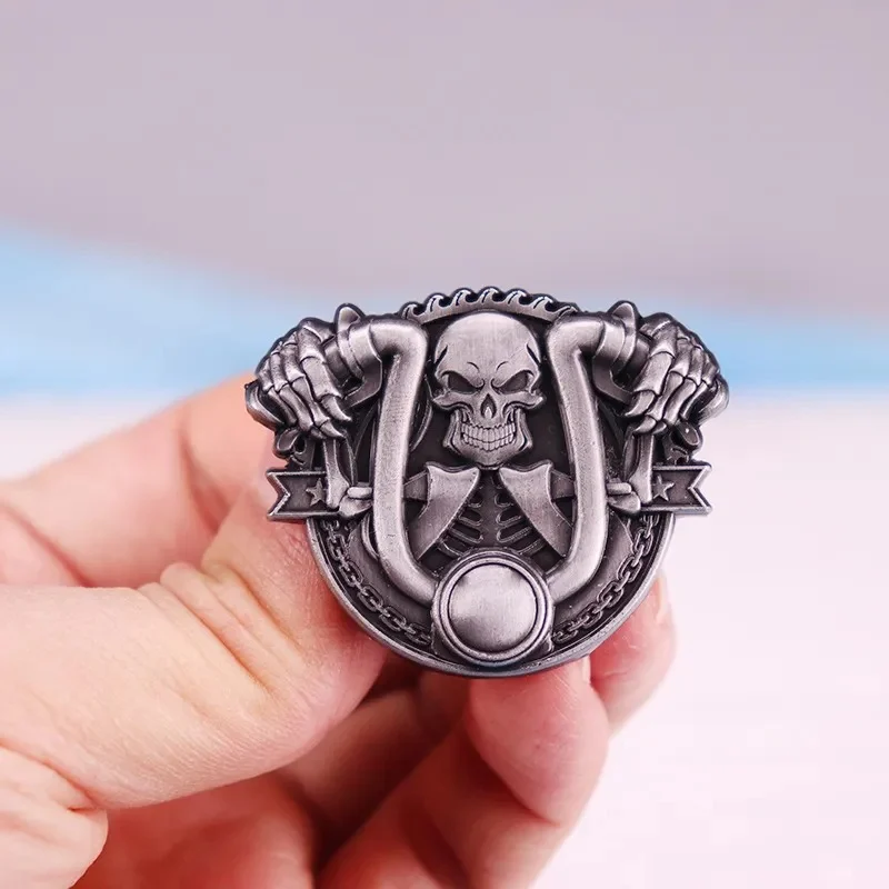 Broche Skull Biker en métal argenté avec motif crâne et fers à cheval tenue par deux mains, détail soigné