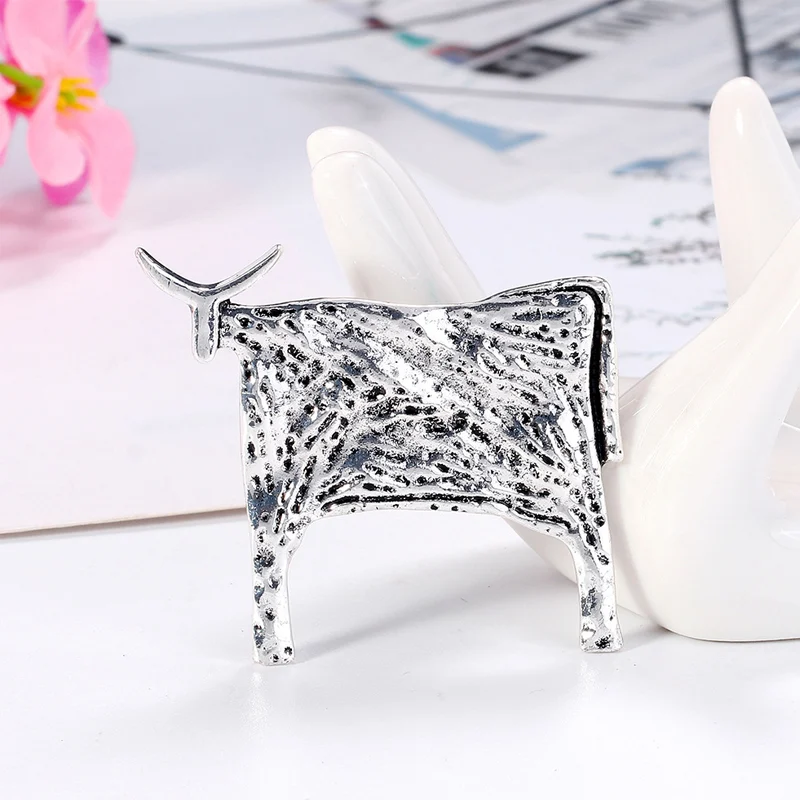 Broche taureau argentée en métal avec texture martelée et finition brillante, vue de côté