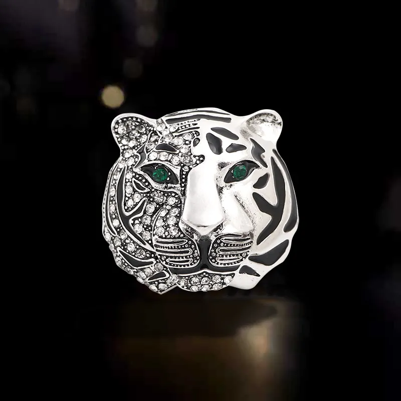 Broche tête de tigre femme en métal argenté avec yeux verts et détails en strass scintillants, motif stylisé avec finition soignée