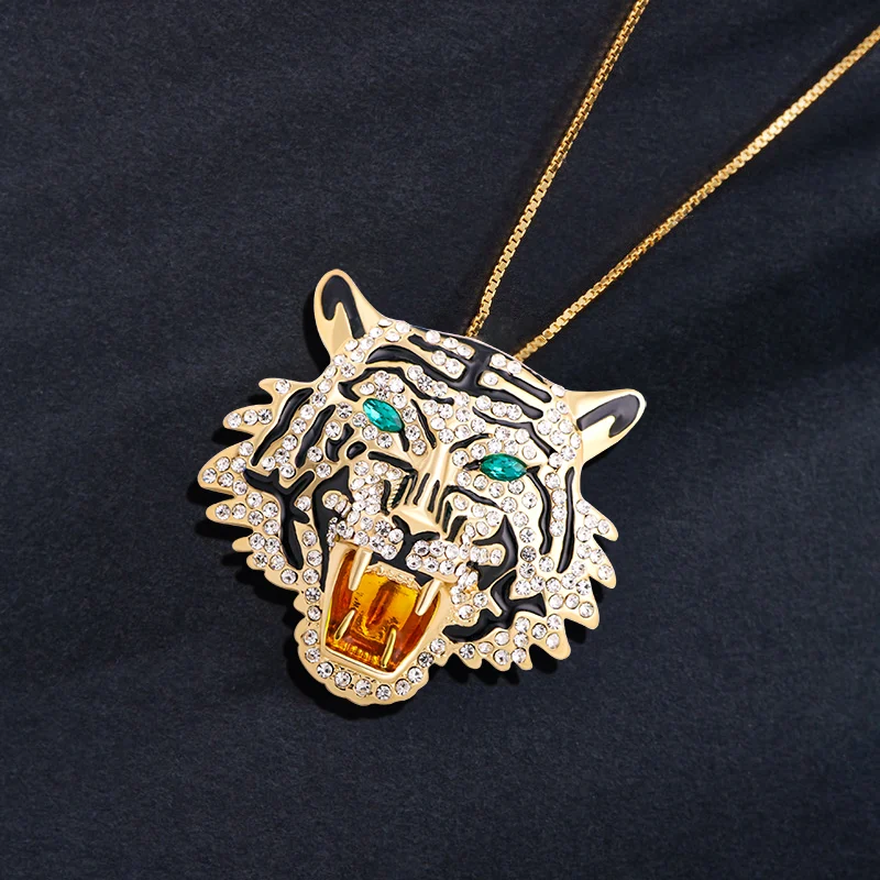 Broche tête de tigre en métal doré avec strass blancs et yeux verts, détail de la gueule ouverte avec finition soignée
