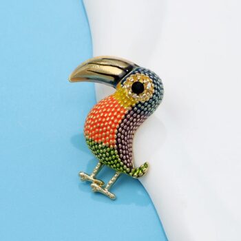 Broche toucan femme en métal doré avec strass multicolores orange, jaune, vert et noir, détail soigné du bec et des plumes