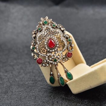 Broche victorienne en métal argenté avec pierres rouges et vertes, ornée de motifs floraux et de perles, avec pendentifs en goutte