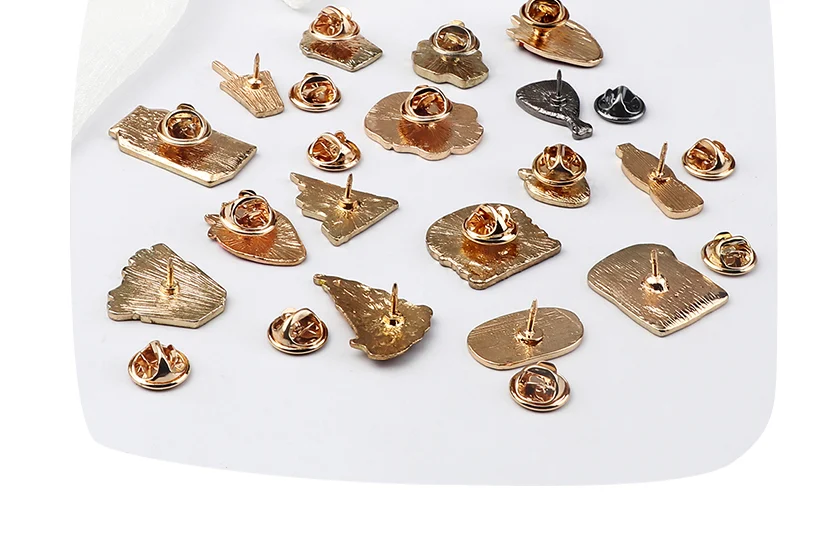 Dos de plusieurs pin's pizza en métal doré avec attaches papillon, vue rapprochée sur les fixations