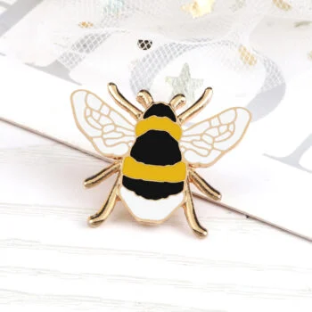 Epingle abeille en métal doré avec motifs noirs et jaunes, ailes translucides décorées de lignes dorées, accessoire de mode raffiné