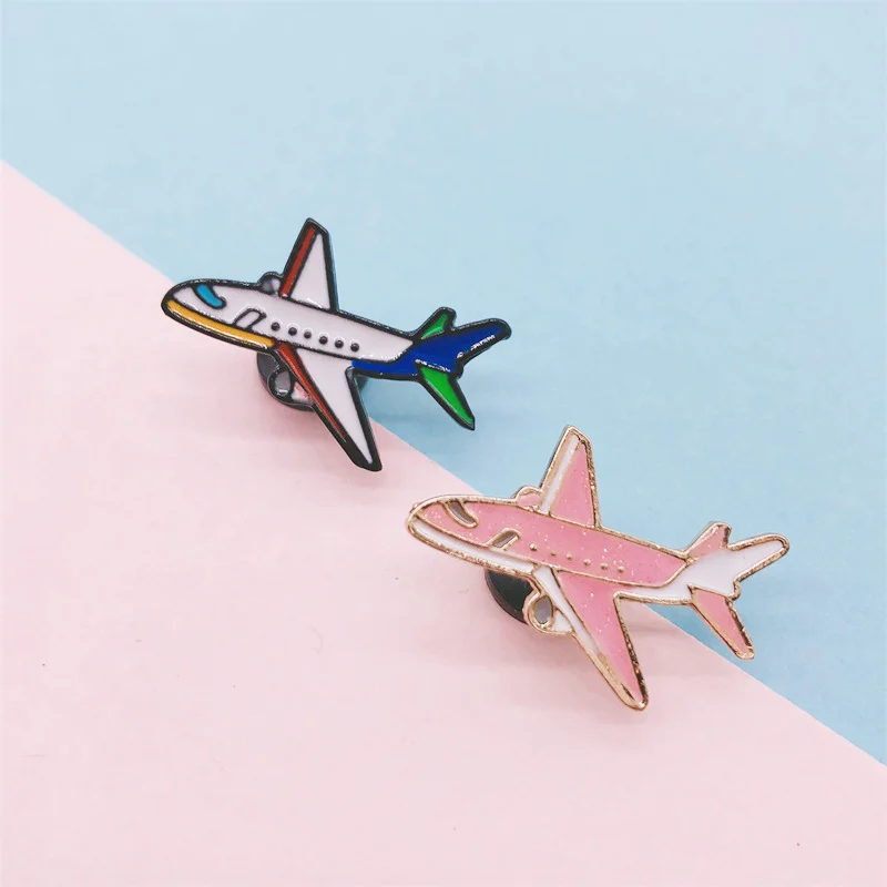 Pin's avion en métal émaillé avec un modèle blanc et bleu et un modèle rose, détail soigné des couleurs et contours