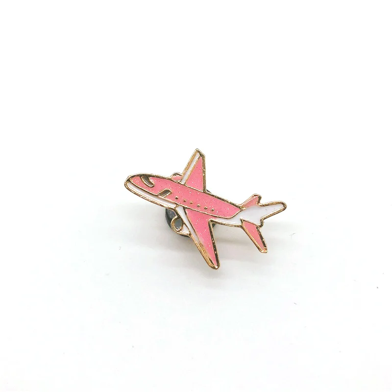 Pin's avion rose en métal avec contour doré, détail soigné sur les ailes et la silhouette