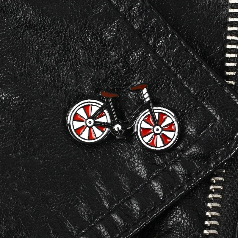 Pin's bicyclette en métal avec roues rouges et blanches sur veste en cuir noir